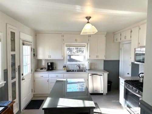 a kitchen with white cabinets and a sink at Bluebird Day - Hill Street Beauty in Bend