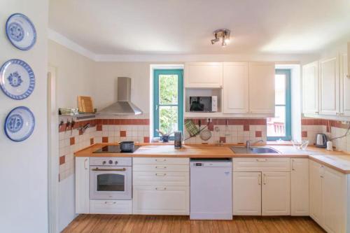 a kitchen with white cabinets and white appliances at Fara Bošín in Křinec