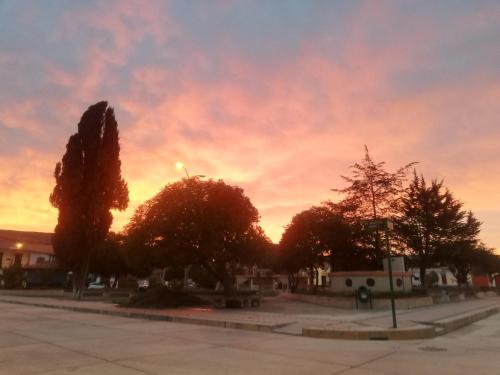 a sunset in a parking lot with trees and a sky at SumaqWasi Huaripampa in Jauja
