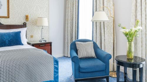 a hotel room with a bed and a blue chair at InterContinental Paris Le Grand by IHG in Paris