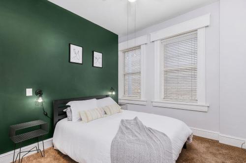 a green bedroom with a bed and two windows at Casa Historia Sleek 2B apt UNIQUE spot downtown in Fort Myers