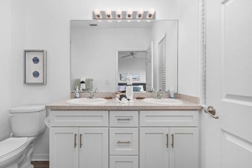 a white bathroom with two sinks and a toilet at Paradise at Hidden Palms Cove in Fort Myers