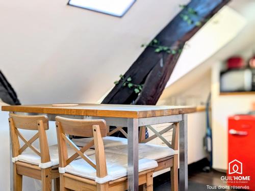 Cette chambre mansardée comprend une table et deux chaises. dans l'établissement Ô Cocon - Central - Climatisé - Poutres apparentes, à Orléans
