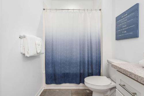 a bathroom with a blue shower curtain and a toilet at Hideaway at Hidden Palms Cove in Fort Myers
