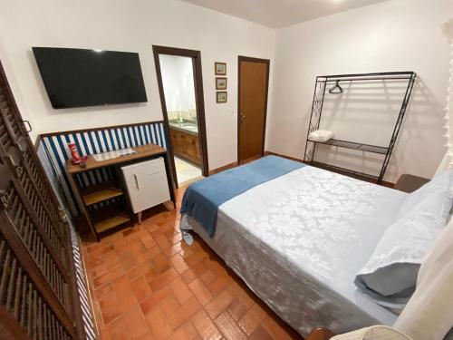 a bedroom with a bed and a flat screen tv at Casarão Coimbra Pousada Colonial in Pirenópolis