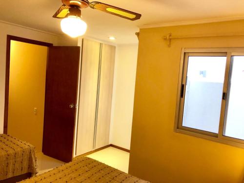 a bedroom with a bed and a window and a ceiling fan at Apartamentos Piriapolis in Piriápolis