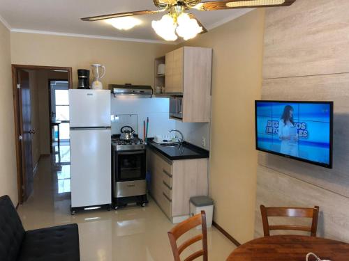 a kitchen with a refrigerator and a tv on a wall at Apartamentos Piriapolis in Piriápolis