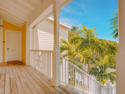 a porch of a house with a white door and palm trees at Valentines Resort & Marina in Harbour Island