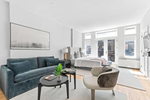 a living room with a blue couch and a bed at Luxe Studio w Juliet Balcony in Upper East in New York