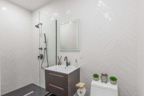 a white bathroom with a sink and a shower at Luxe Studio w Juliet Balcony in Upper East in New York