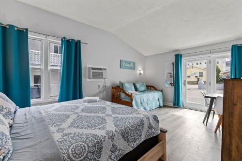 1 dormitorio con cortinas azules, 1 cama y 1 silla en Cozy King Suite Steps to the Beach (441), en Old Orchard Beach