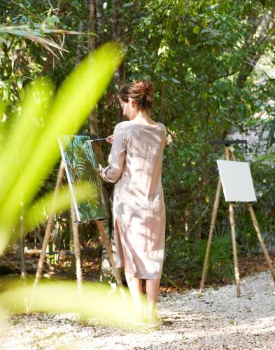 a woman in a dress painting on an easel at Viceroy Riviera Maya, a Luxury Villa Resort - Adults Only in Playa del Carmen