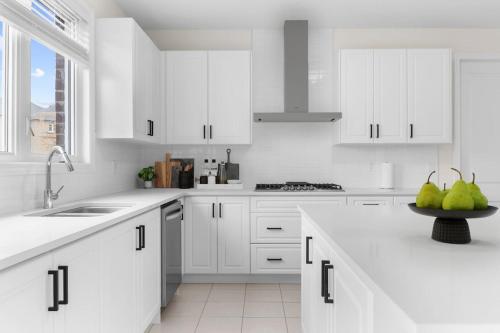 a white kitchen with white cabinets and pears on the counter at Prime Peterborough - 4BR and Office, Newly Renovated in Peterborough