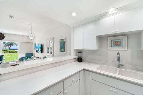 a white kitchen with white cabinets and a sink at Beachfront Condo next to Ritz in West Bay