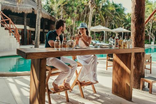 a man and woman sitting at a table by a pool at Viceroy Riviera Maya, a Luxury Villa Resort - Adults Only in Playa del Carmen