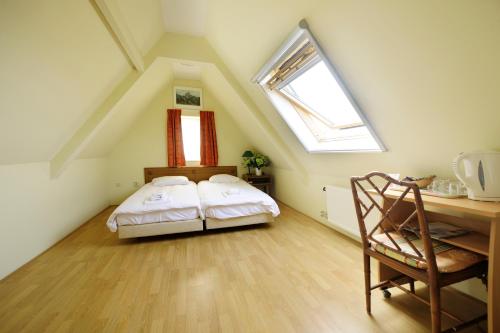 a attic bedroom with a bed and a desk and a window at De Gouden Karper in Rustenburg