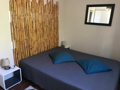 une chambre avec un lit avec des oreillers bleus et un miroir dans l'établissement ENTRE TERRE ET MER, à Ajaccio