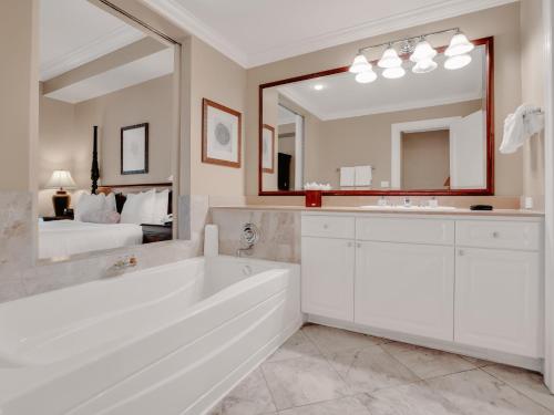 a white bathroom with a tub and a large mirror at Valentines Resort & Marina in Harbour Island