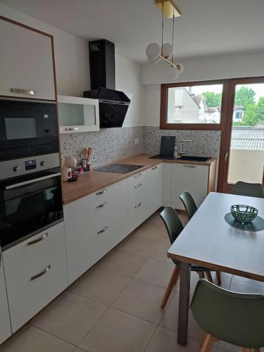 une cuisine avec des armoires blanches et une table avec des chaises dans l'établissement Appartement neuf, vue sur parc, 5 minutes à pied du centre historique et piéton, à Pau