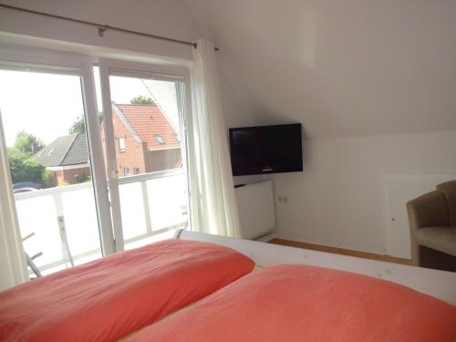 a bedroom with a bed and a window with a television at Ferienhaus Anna in Greetsiel