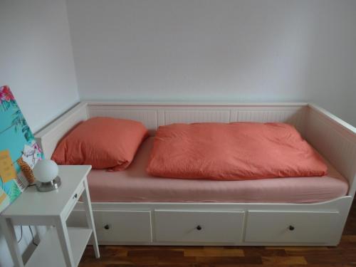 a bed with two red pillows on it next to a table at Ferienhaus Anna in Greetsiel