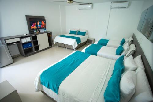 a hotel room with two beds and a television at Hotel Poblado Coveñas in Coveñas