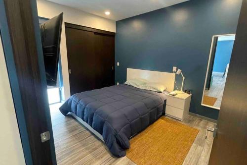 a bedroom with a blue bed and a mirror at Loft MIXCOAC cerca de Todo - Trabajo o descanso - Alberca y Gym in Mexico City