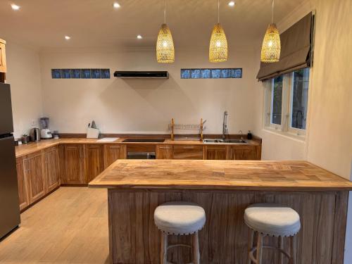 a kitchen with a large wooden island with bar stools at Suara Jiwa Luxury Villas with Private Pool in Ubud