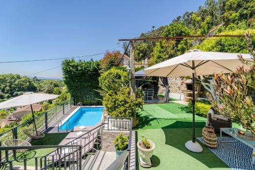 an outdoor patio with a swimming pool and umbrellas at Casa das Caldas in Caldelas