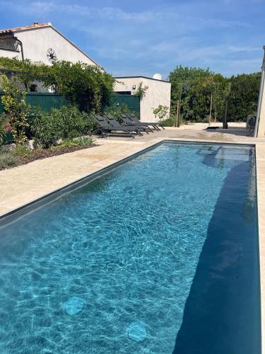 une piscine avec de l'eau bleue devant une maison dans l'établissement La Maison de Luna, à Saint-Rémy-de-Provence