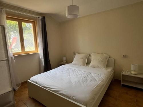 ein Schlafzimmer mit einem Bett mit weißen Laken und einem Fenster in der Unterkunft Gîte 6 personnes avec piscine in Agnac