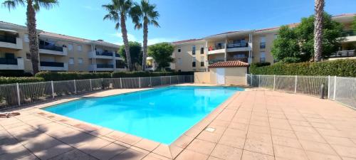 une piscine devant un immeuble avec des palmiers dans l'établissement L’azuréenne vue sur piscine, à La Seyne-sur-Mer