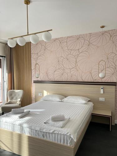 a bedroom with a large bed and a chair at Pensiunea Villa D'Amici in Moşniţa Nouă
