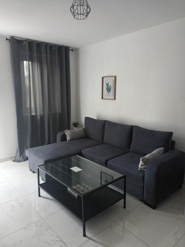 a living room with a blue couch and a glass coffee table at Maison meublée avec parking in Moulins