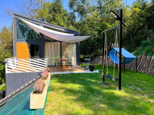 a backyard with a swing and a house at Najwyzej - domek z sauną w Gródku nad Dunajcem nad Jeziorem Rożnowskim in Gródek Nad Dunajcem