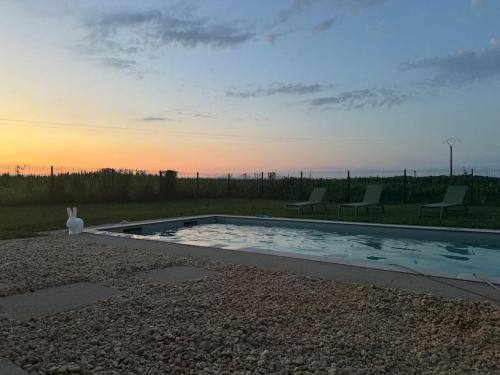 a swimming pool with two chairs and a sunset at Magnifique Villa 4 chambres avec piscine in Wolfersdorf