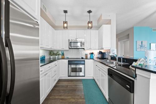a kitchen with white cabinets and a stainless steel refrigerator at Beach Colony East 14D in Pensacola