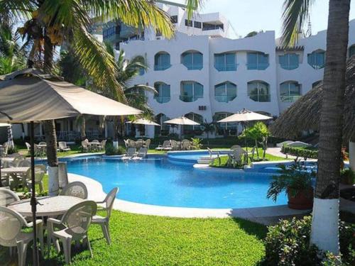 a swimming pool with tables and chairs and a hotel at Playa Caracol Hotel & Spa in Veracruz