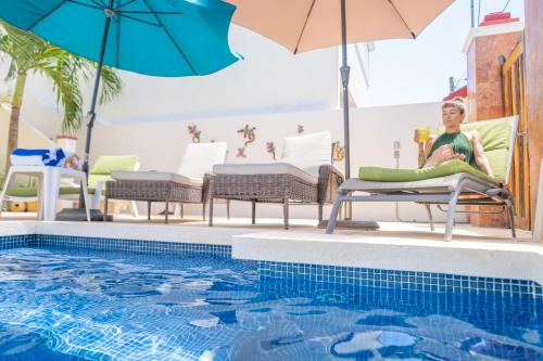 a woman sitting in a chair next to a swimming pool at Villas Keh in Isla Mujeres