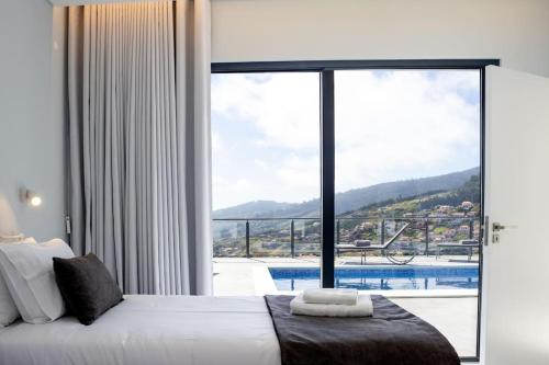 a bedroom with a large window with a view of a pool at Vila Indigo in Arco da Calheta