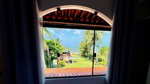 a window view of the ocean from a resort at JaParaíso Pousada Ateliê in Japaratinga