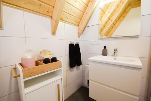 a white bathroom with a sink and a mirror at Ferienhaus Mellumplate 23 in Dorum Neufeld