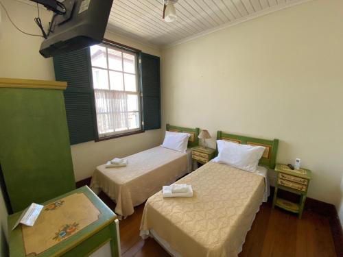 a small room with two beds and a window at Pousada do Duque in Lambari