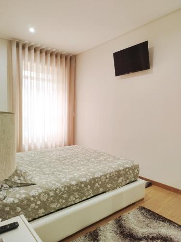 a bedroom with a bed and a television on the wall at Douro Residence Porto Gaia in Vila Nova de Gaia