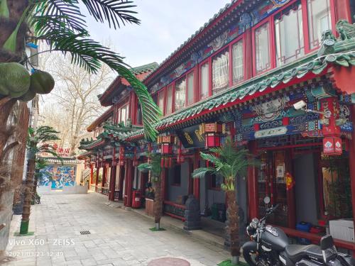 a building with a palm tree in front of a street at Qinfu Hotel Beijing Nanluogu Lane Houhai in Beijing