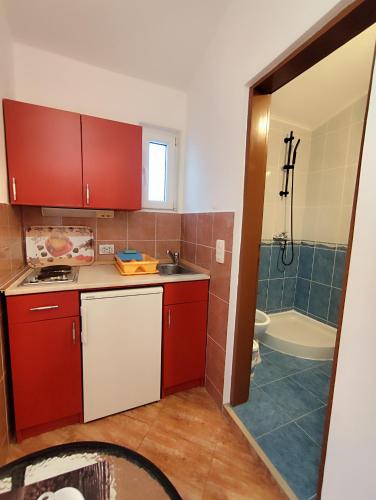 a kitchen with red cabinets and a sink and a tub at Apartmani Šušanj in Bar