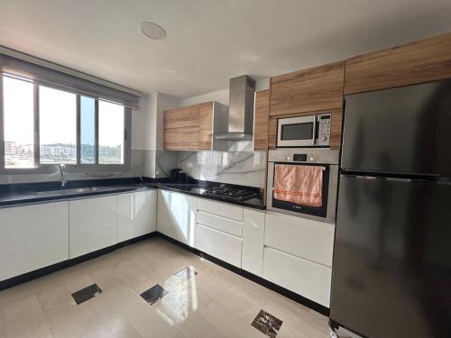 Una cocina con gabinetes blancos y un refrigerador de acero inoxidable. en Sérénité & Confort - Agadir, en Agadir