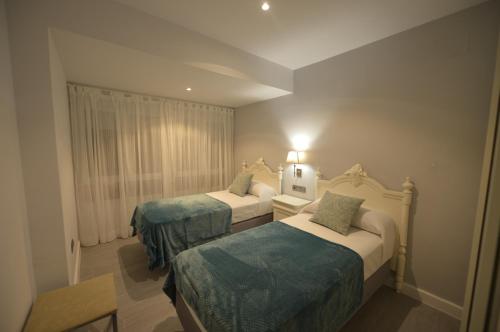 Habitación de hotel con 2 camas con sábanas azules en Apartamento Victoria, en Cádiz