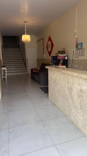 a lobby with a counter and a couch and stairs at Hotel Veneza in Rio do Sul