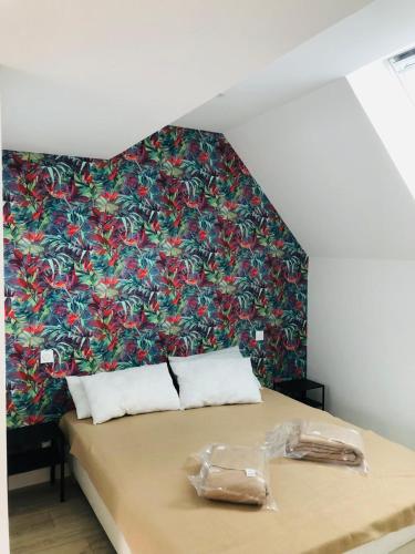 - un lit dans un dortoir avec un mur fleuri dans l'établissement Charmante maison, à Château-Gontier